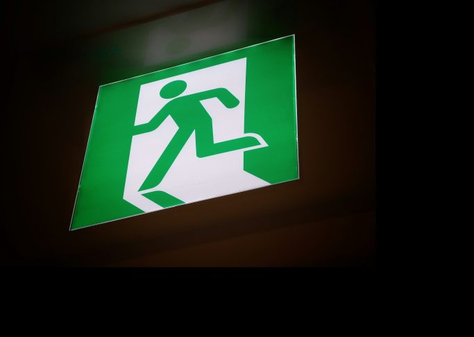 Grünes Schild mit einem Laufenden Mann, der auf einen Ausgang zeigt.