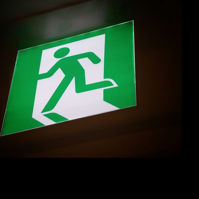 Grünes Schild mit einem Laufenden Mann, der auf einen Ausgang zeigt.