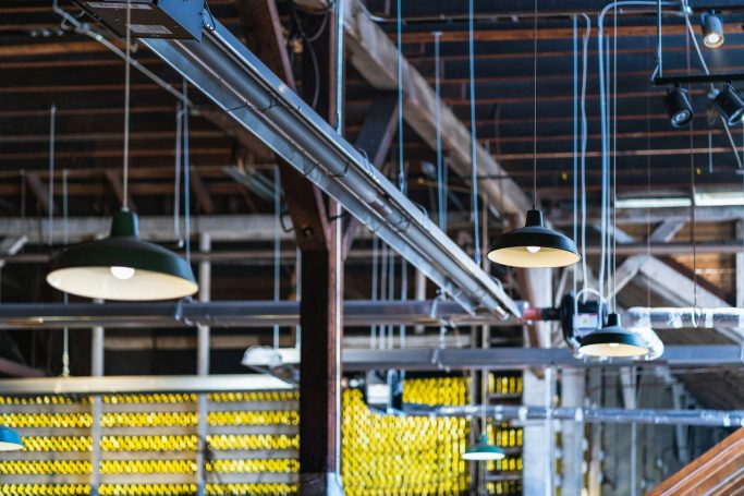 Helle Industriebeleuchtung in einer Lagerhalle mit hängenden Lampen und Holzstruktur.