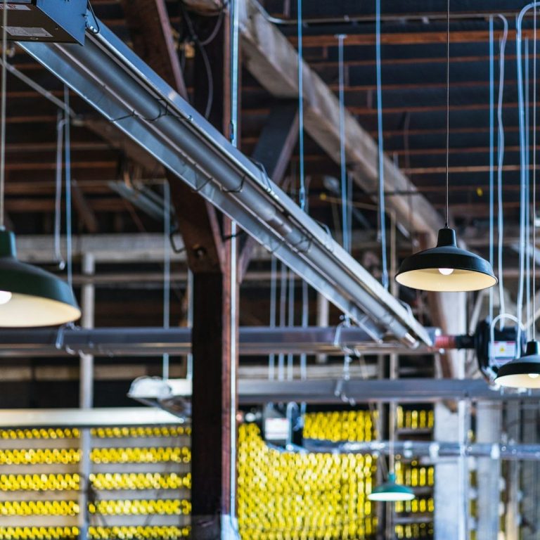 Industrielle Innenansicht mit hängenden Lampen und gestreiften Wänden.